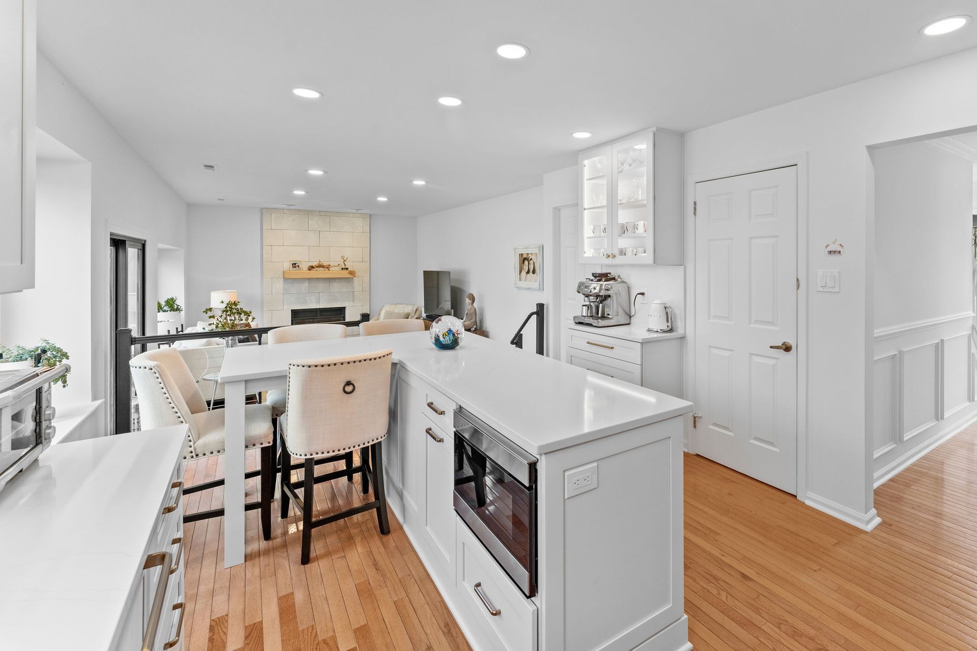 Bright white kitchen with island, bar stools, hardwood floors, and stainless appliances In Bucks Country PA