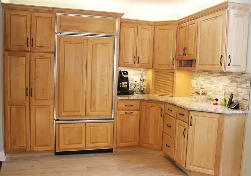 Warm wood kitchen with built-in refrigerator, cabinets, and beige countertops In Bucks County PA