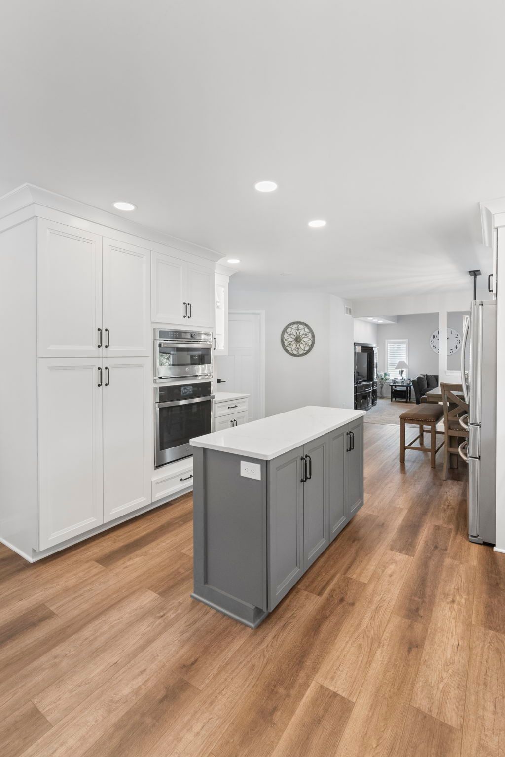 Bright modern kitchen with white cabinets, wood floors, and a gray island leading to a dining area In Bucks County PA