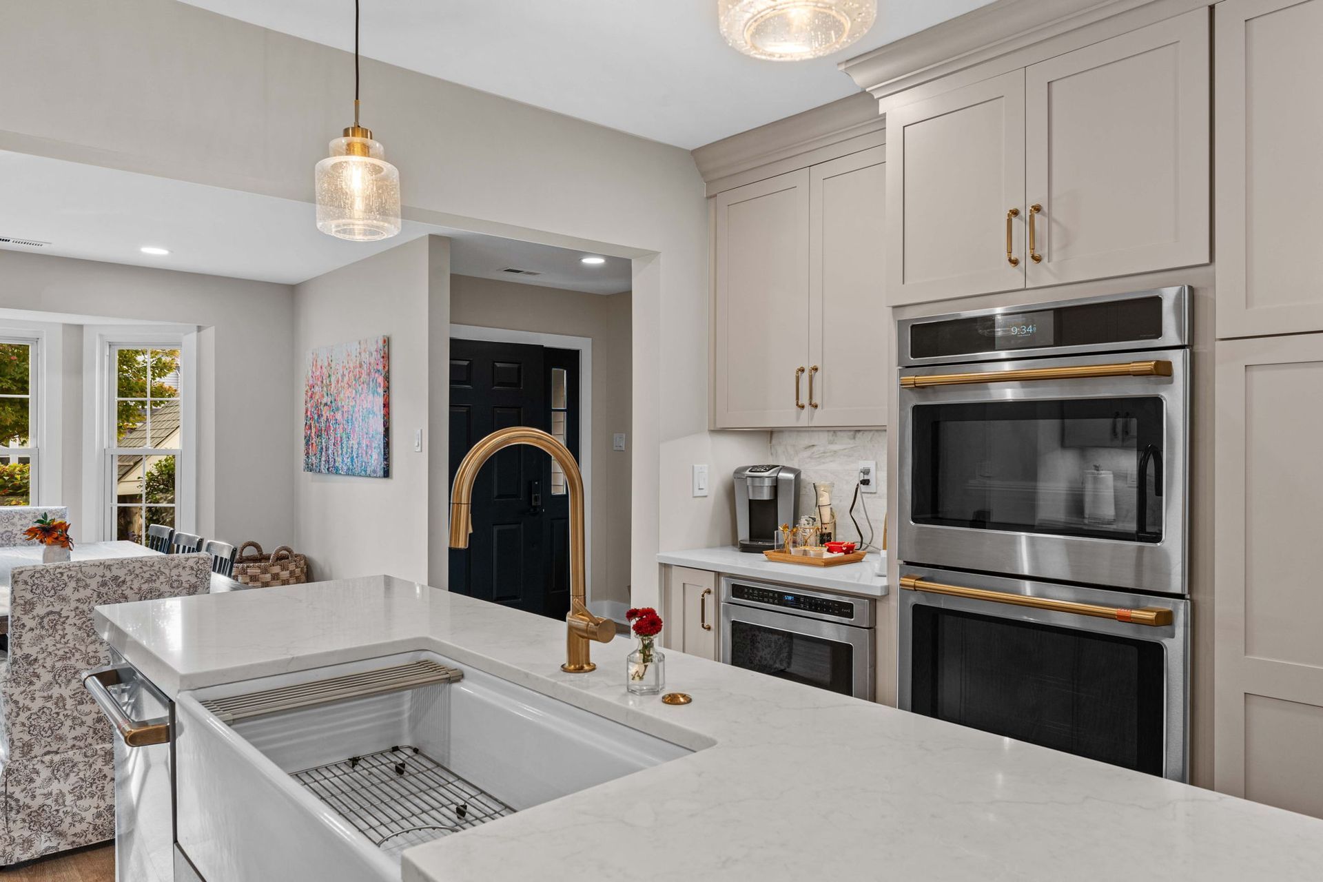 Modern kitchen with gray cabinets, white island sink, and built-in stainless steel ovens in Bucks County PA