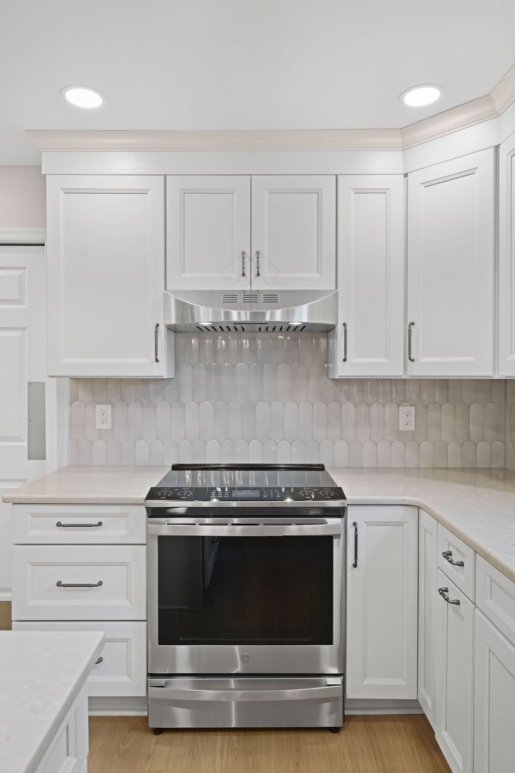 Modern white kitchen with stainless steel stove and light gray backsplash in Bucks County PA