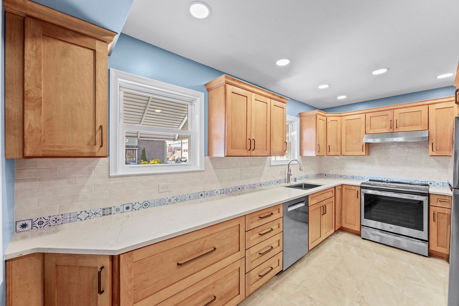 Bright kitchen with light wood cabinets, white countertops, stainless appliances, and a window above the sink In Bucks County PA