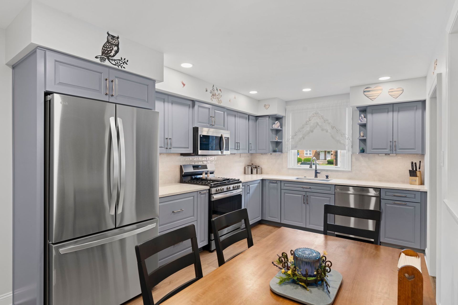 Bright modern kitchen with gray cabinets, stainless steel appliances, and a wooden table with chairs In Bucks County PA
