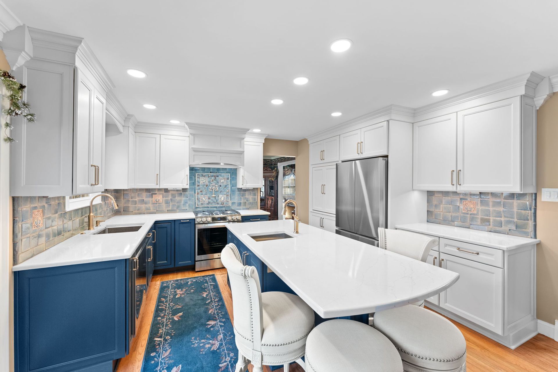Bright modern kitchen with white cabinets, blue island, marble counters, and barstools  In Bucks County PA