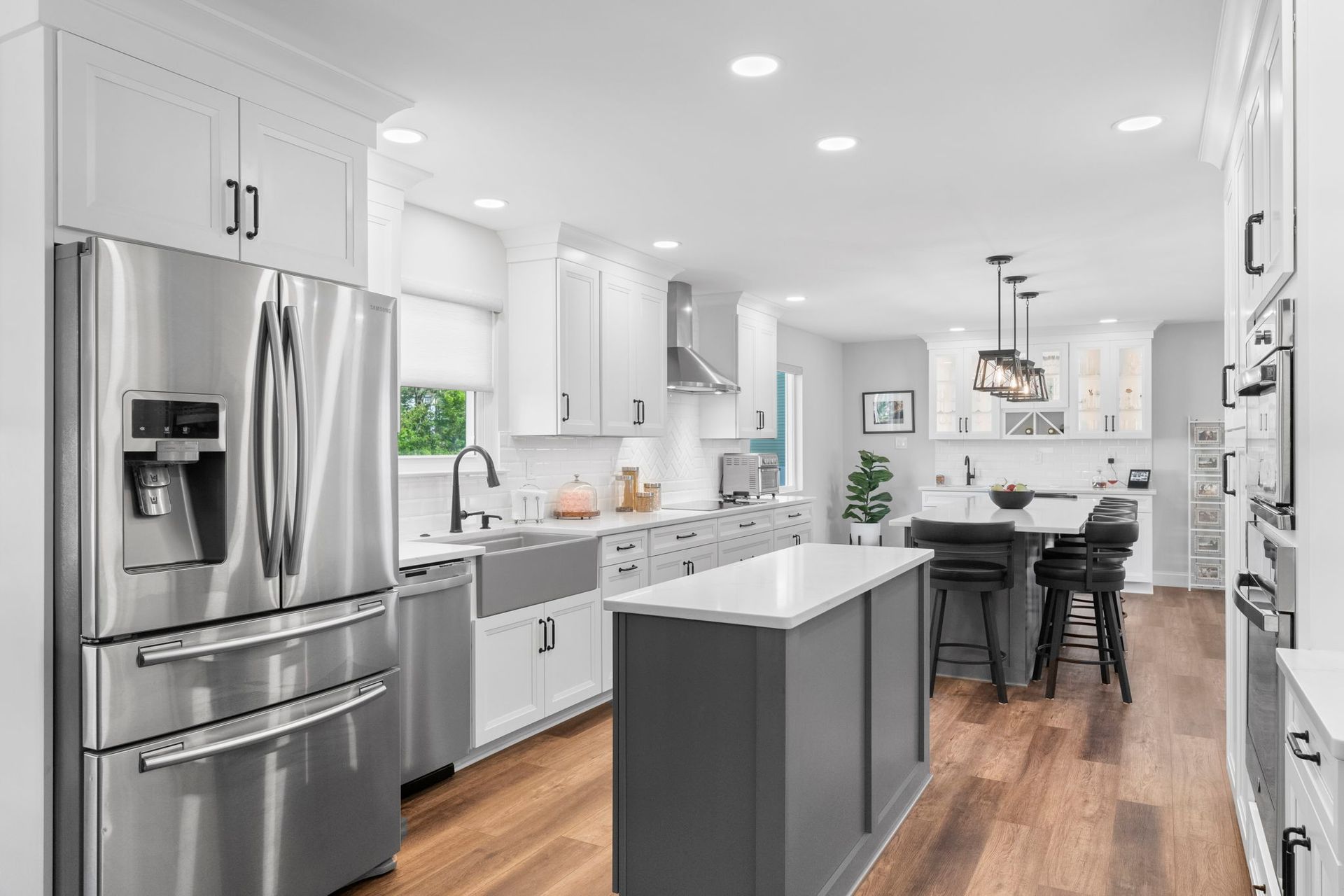 Bright modern kitchen with stainless steel appliances, gray island, white cabinets, and hardwood floors In Bucks County PA