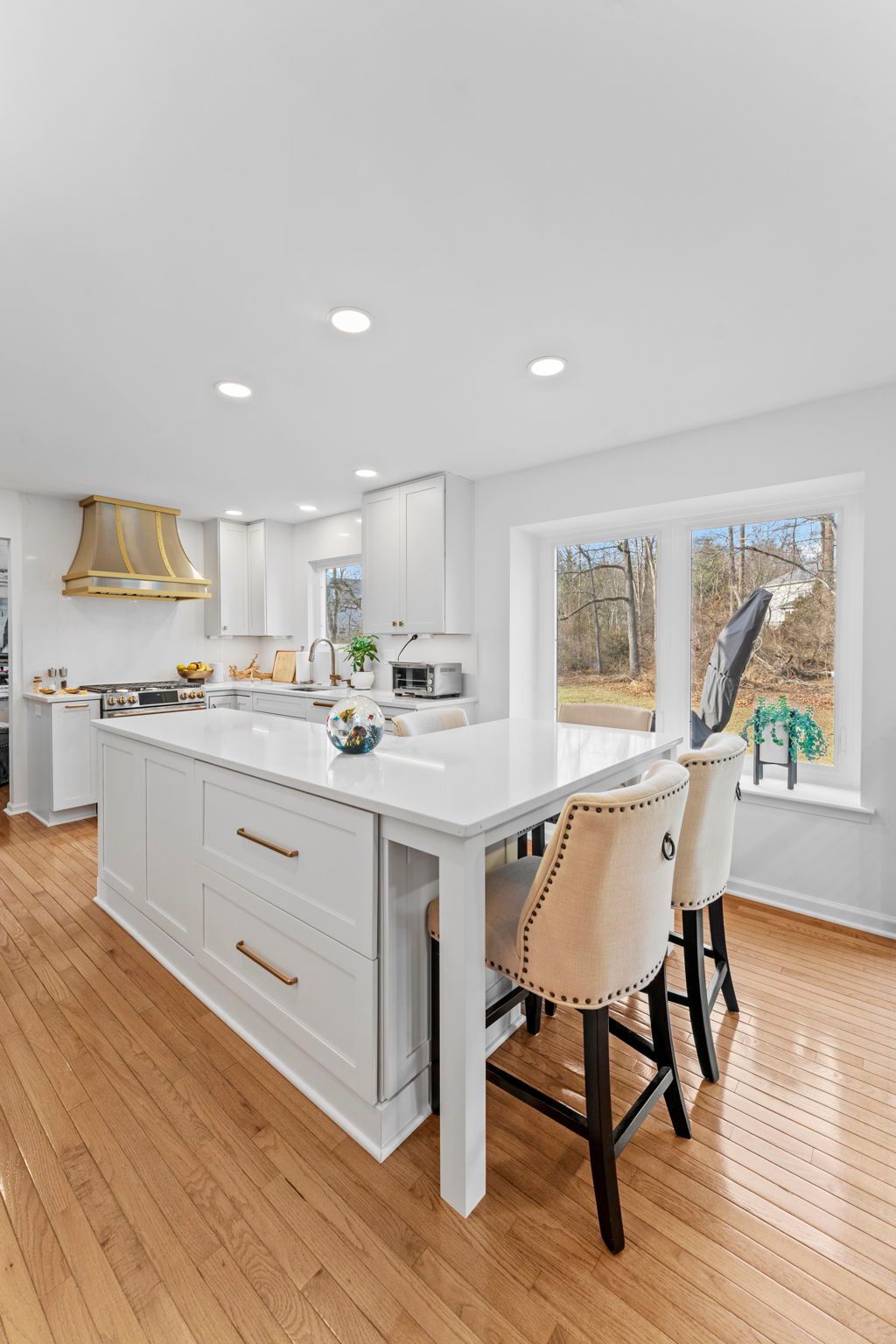 Bright white kitchen with island, barstools, and large window overlooking trees In Bucks Country PA