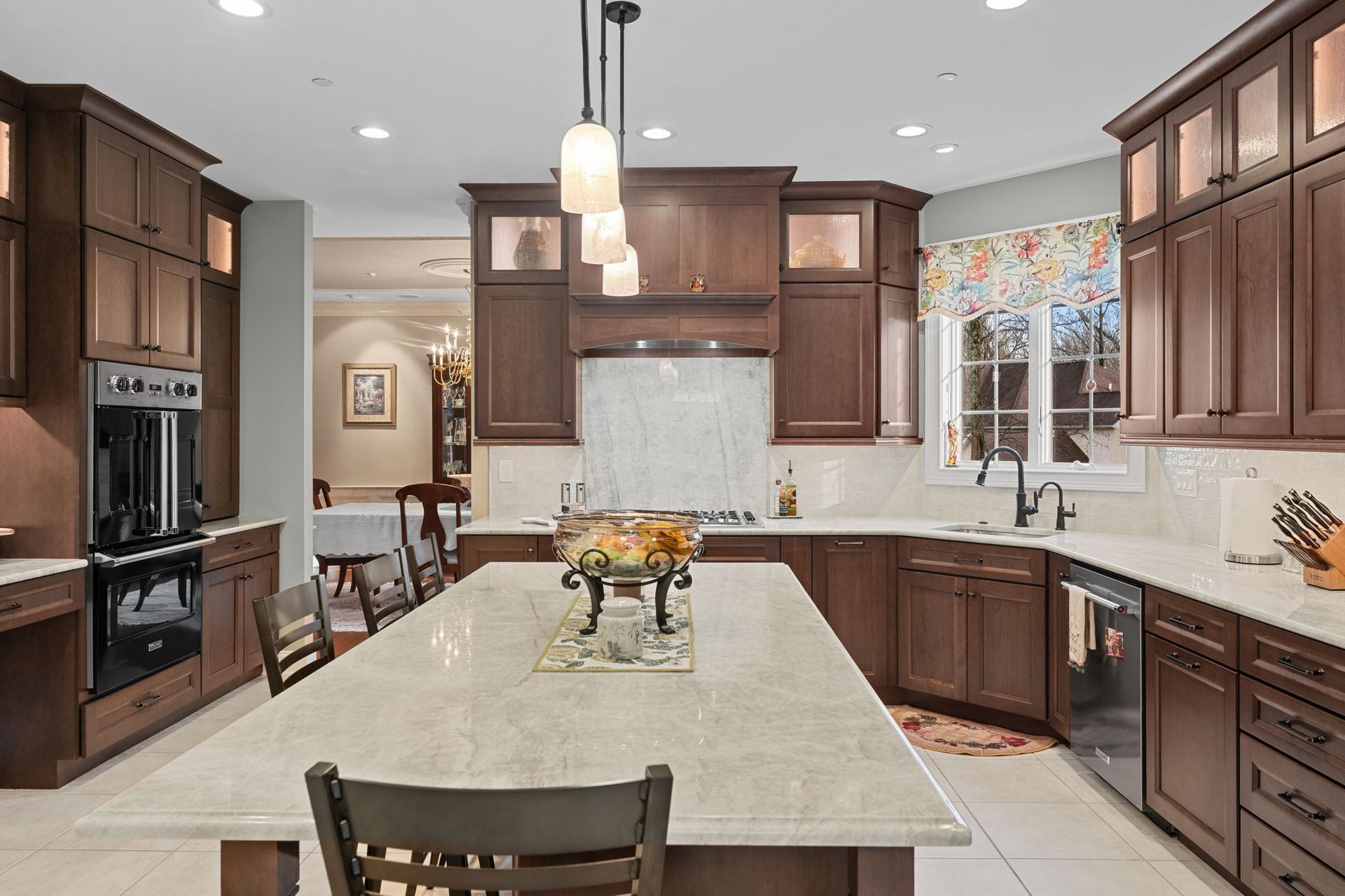 Modern kitchen with dark wood cabinets, white island, and pendant lights In Bucks Country PA