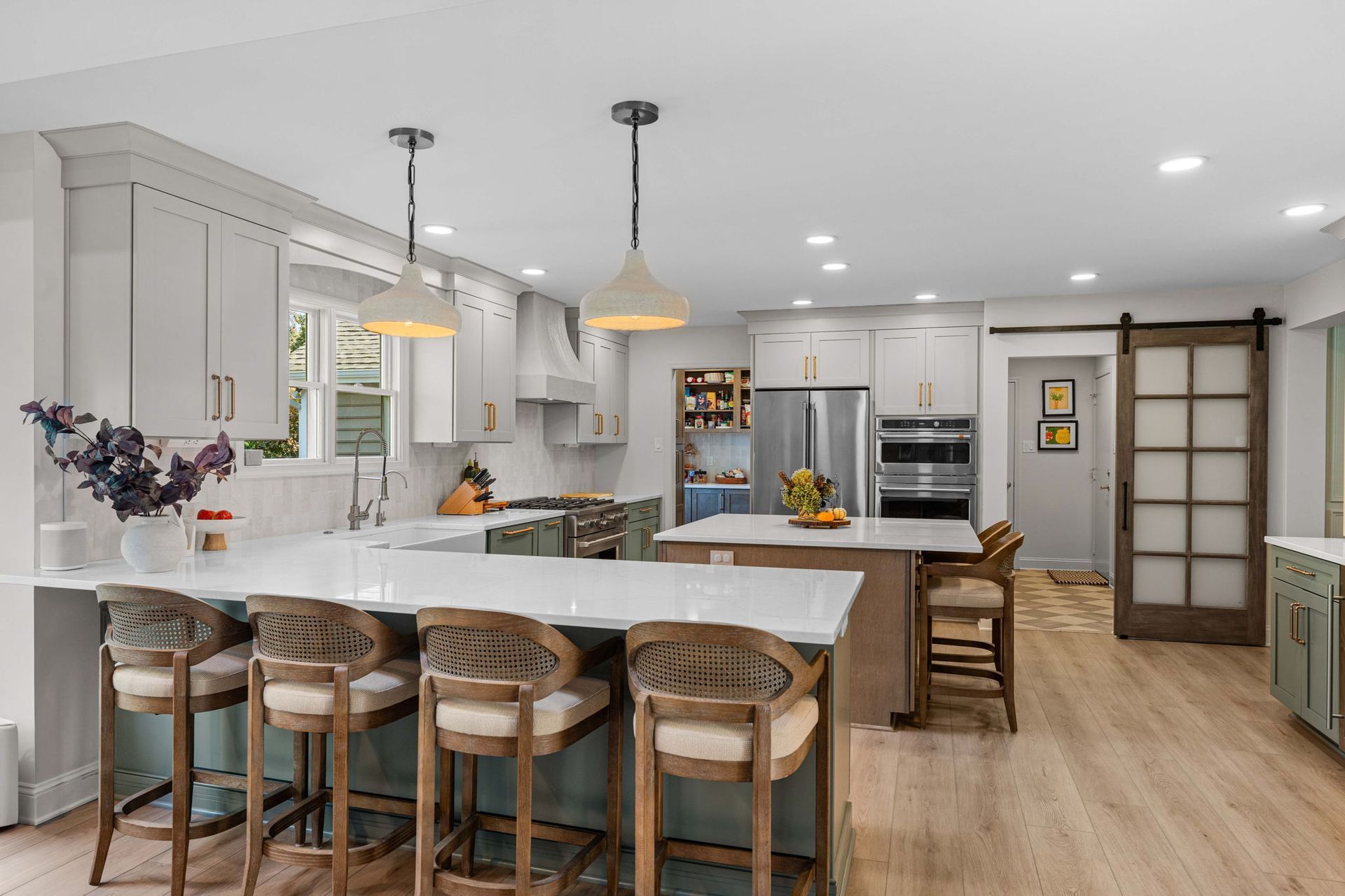 Bright modern kitchen with white cabinets, island seating, stainless steel appliances, and wood floors In Bucks Country PA
