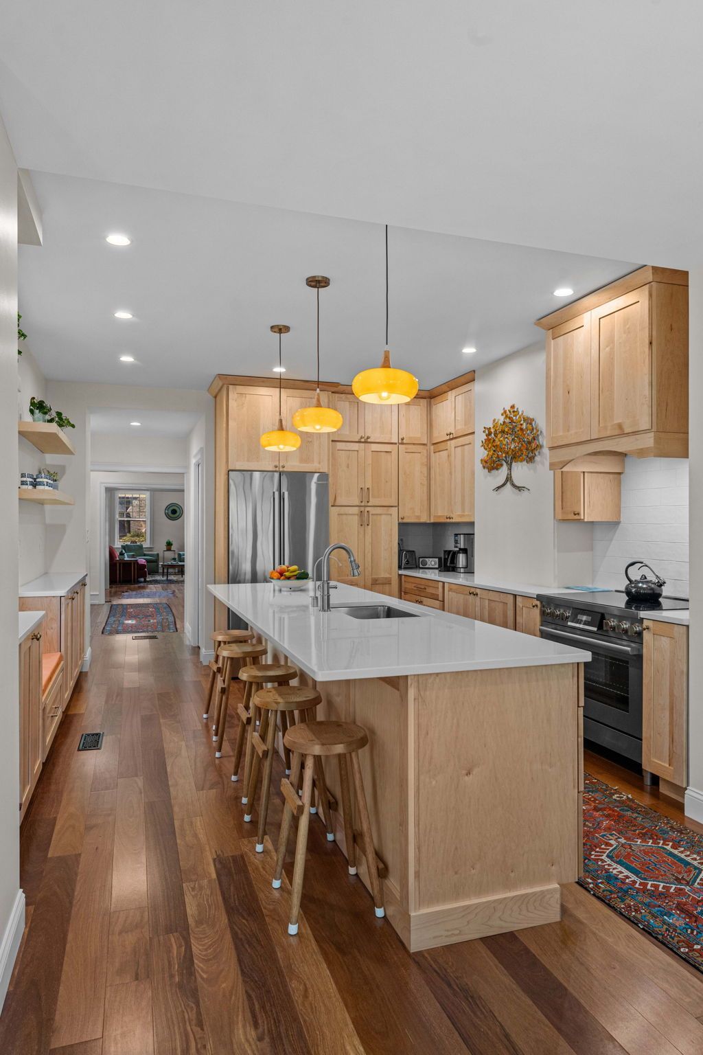 Modern kitchen with wood cabinets, long island, bar stools, and warm pendant lights In Bucks County PA