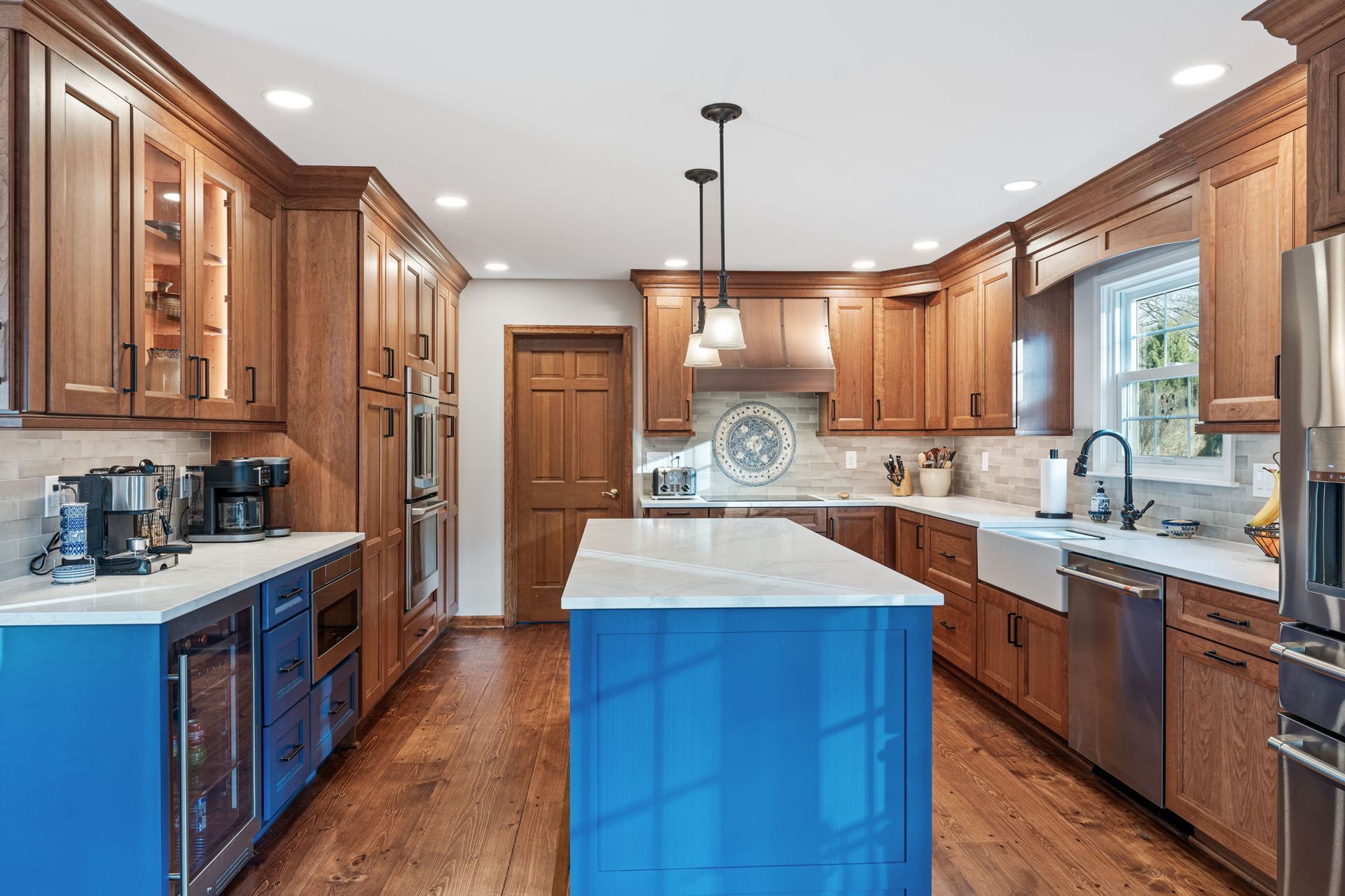 Bright kitchen with wood cabinets, stainless appliances, and a blue island centerpiece In Bucks County PA
