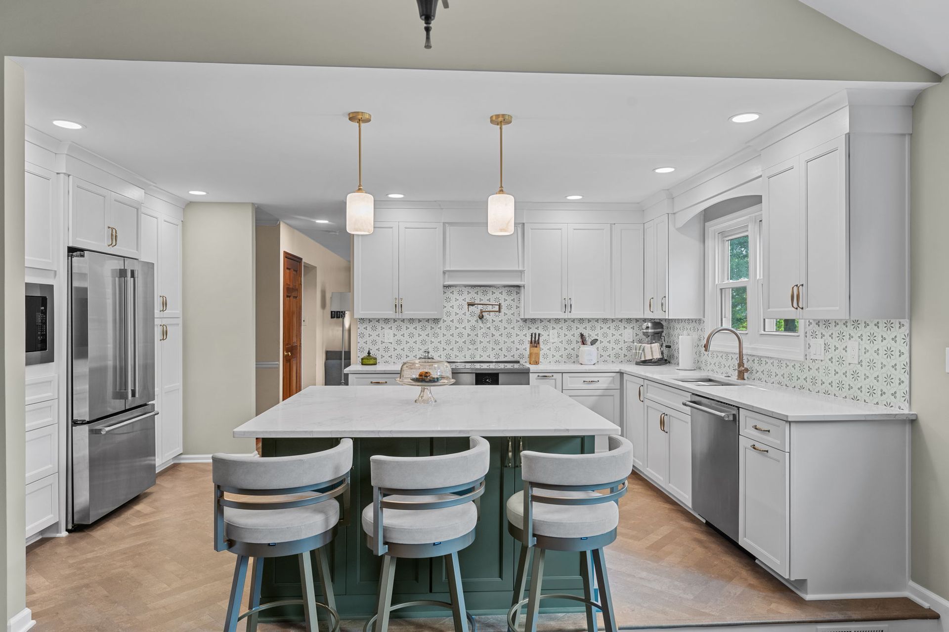 Bright modern kitchen with white cabinets, island seating, stainless appliances, and mosaic backsplash In Bucks Country PA