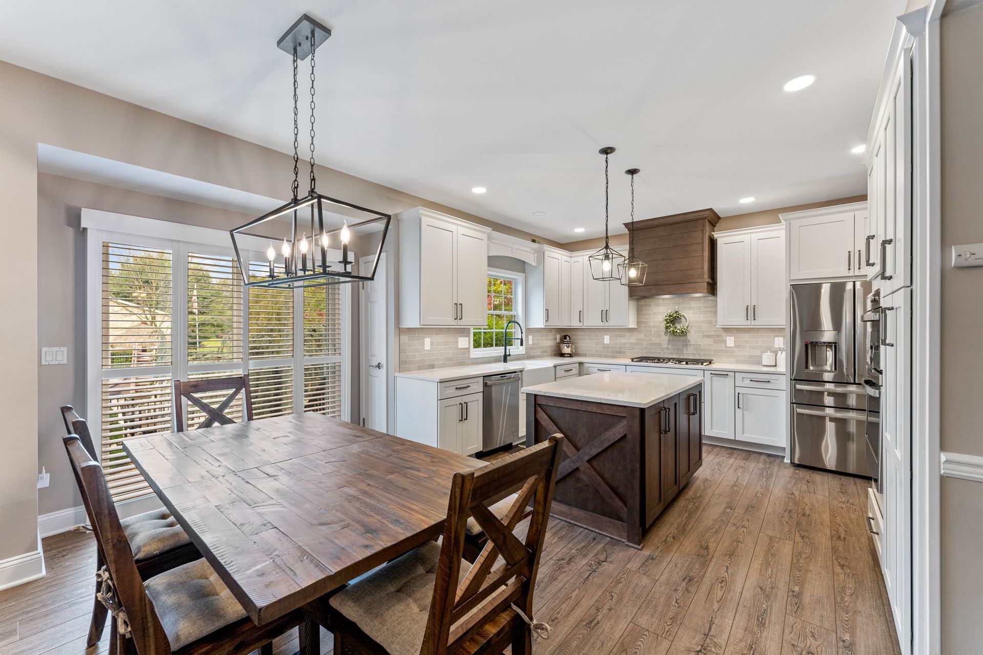 Open kitchen with white cabinets, island, dining table, and large windows overlooking a wooded view  In Bucks County PA