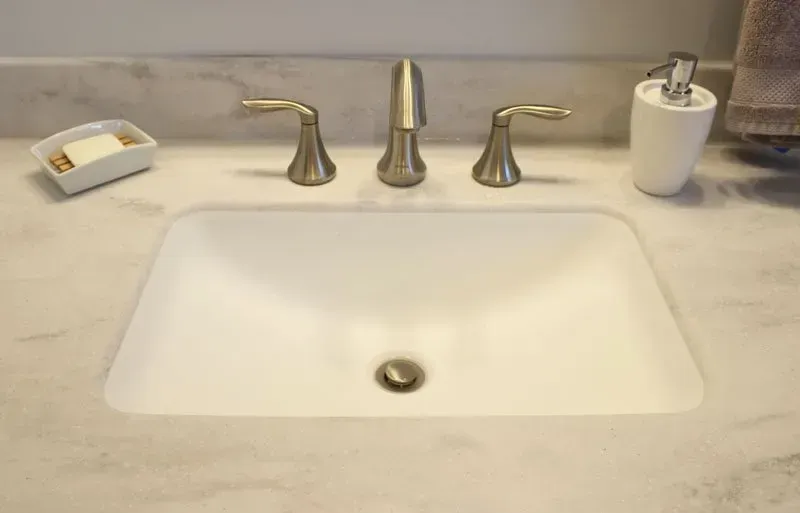 Bathroom sink with chrome faucet, soap dish, and toothbrush cup on a beige countertop  In Bucks County PA