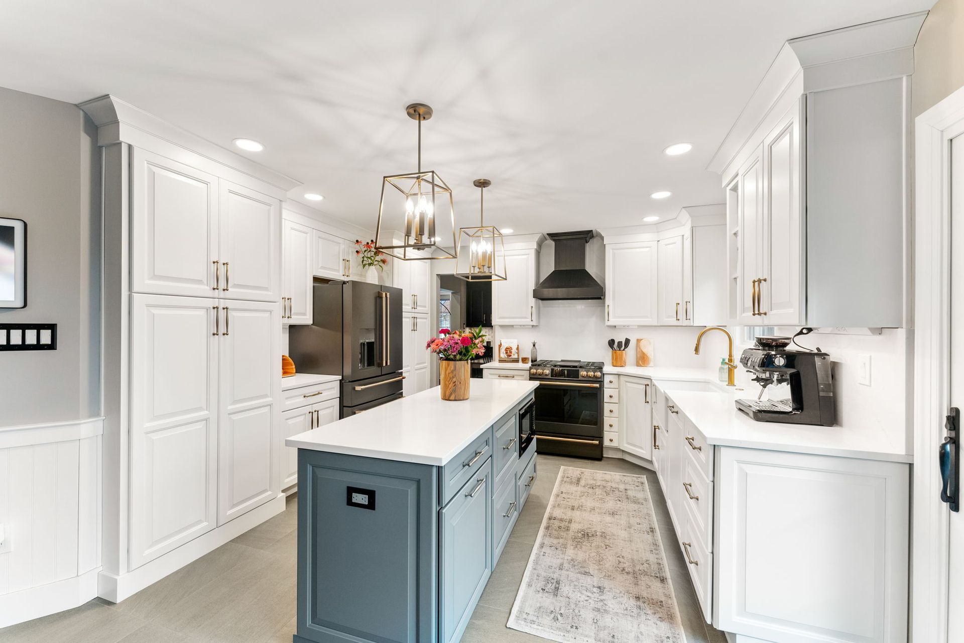 Bright white kitchen with a blue island, stainless appliances, and pendant lighting In Bucks Country PA