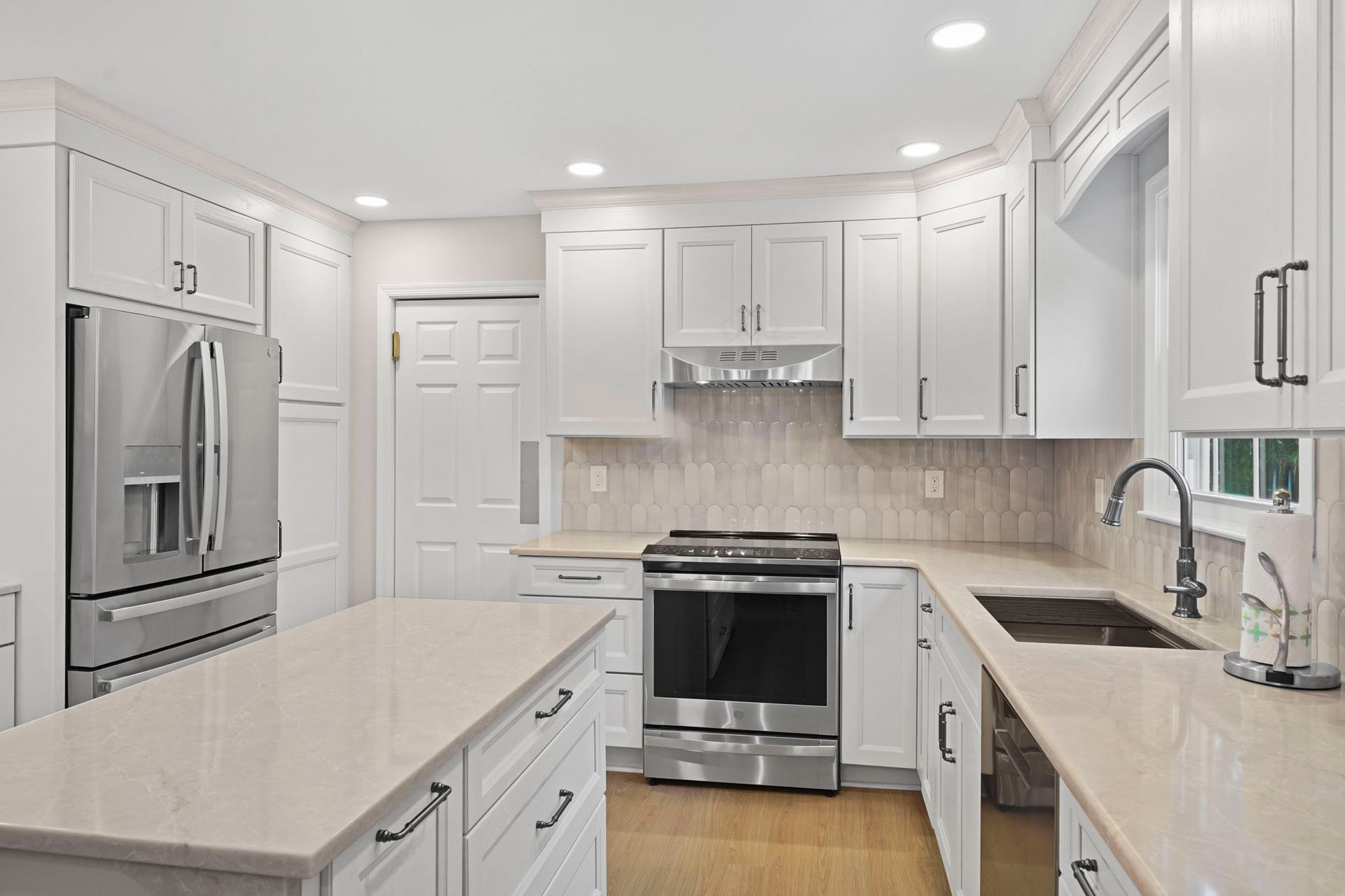 Bright modern kitchen with white cabinets, stainless steel appliances, island, and light countertops in Bucks County PA