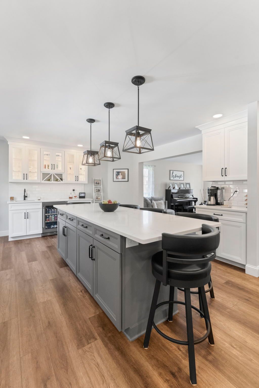 Bright modern kitchen with gray island, white cabinets, pendant lights, and a black barstool In Bucks County PA