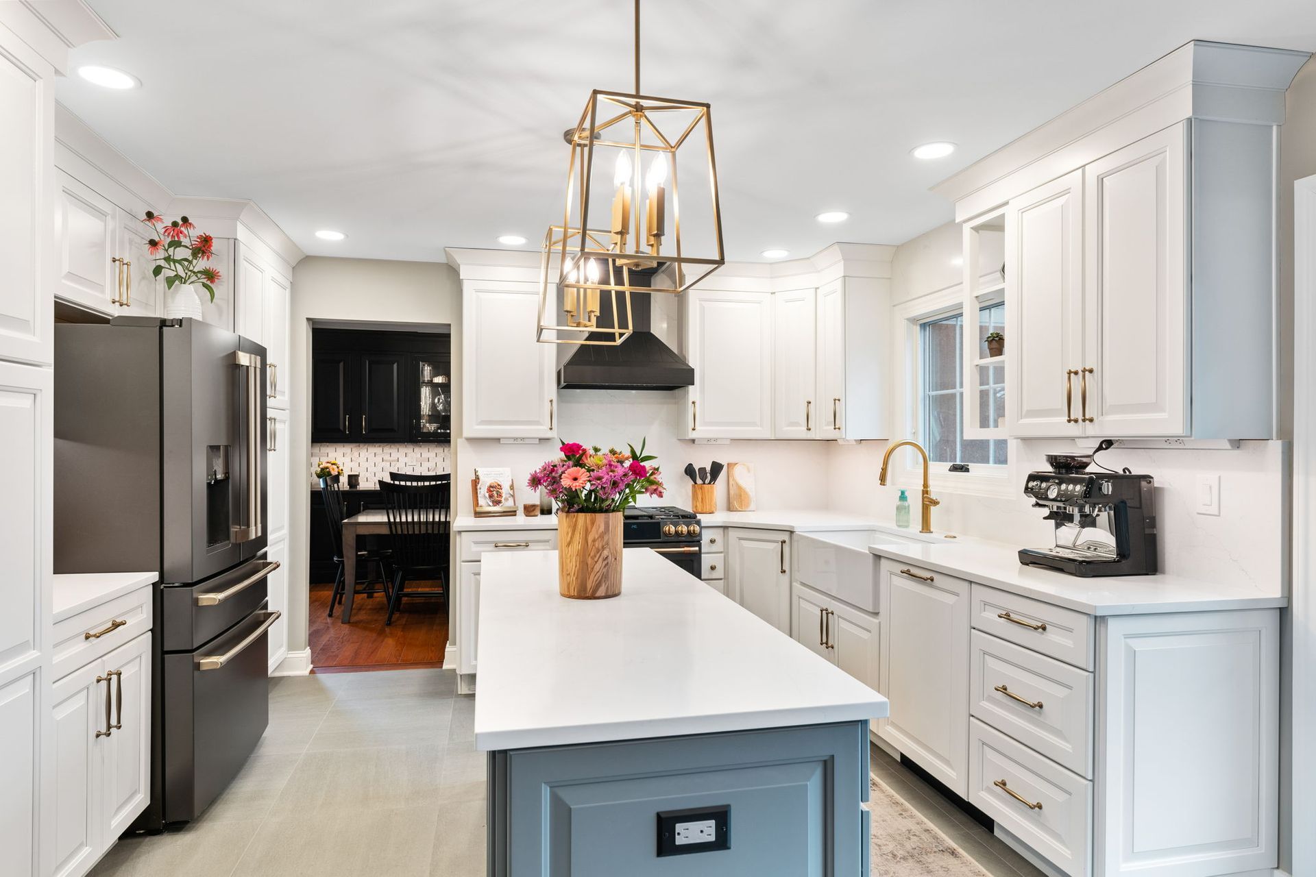 Bright white modern kitchen with an island, stainless fridge, and gold pendant lights In Bucks Country PA