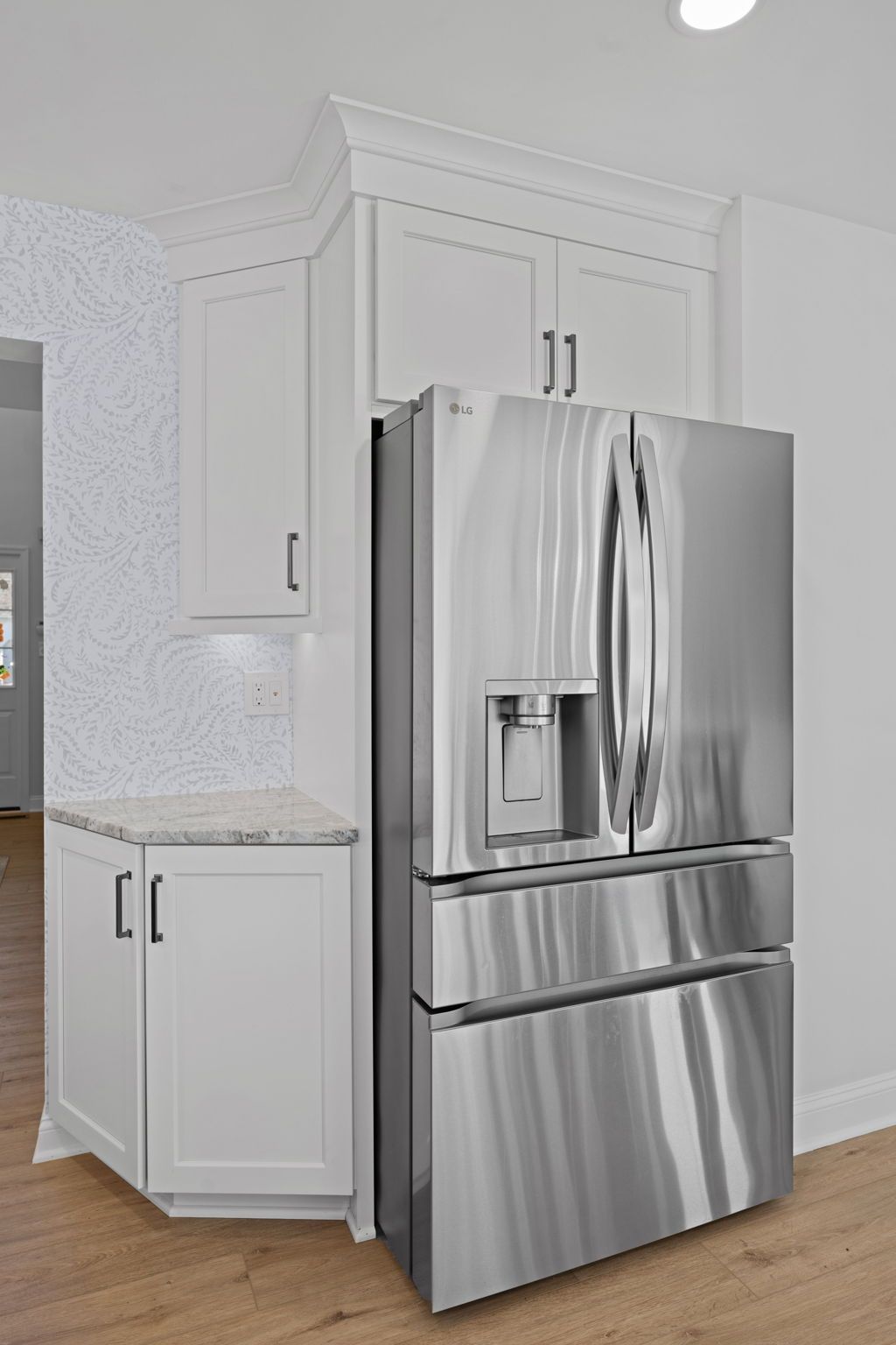 Stainless steel French door refrigerator in a white kitchen with cabinets and wood flooring  In Bucks County PA