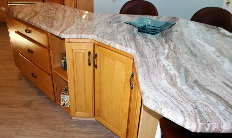 Kitchen island with wood cabinets and gray marble countertop, with a blue glass bowl on top in Washington 