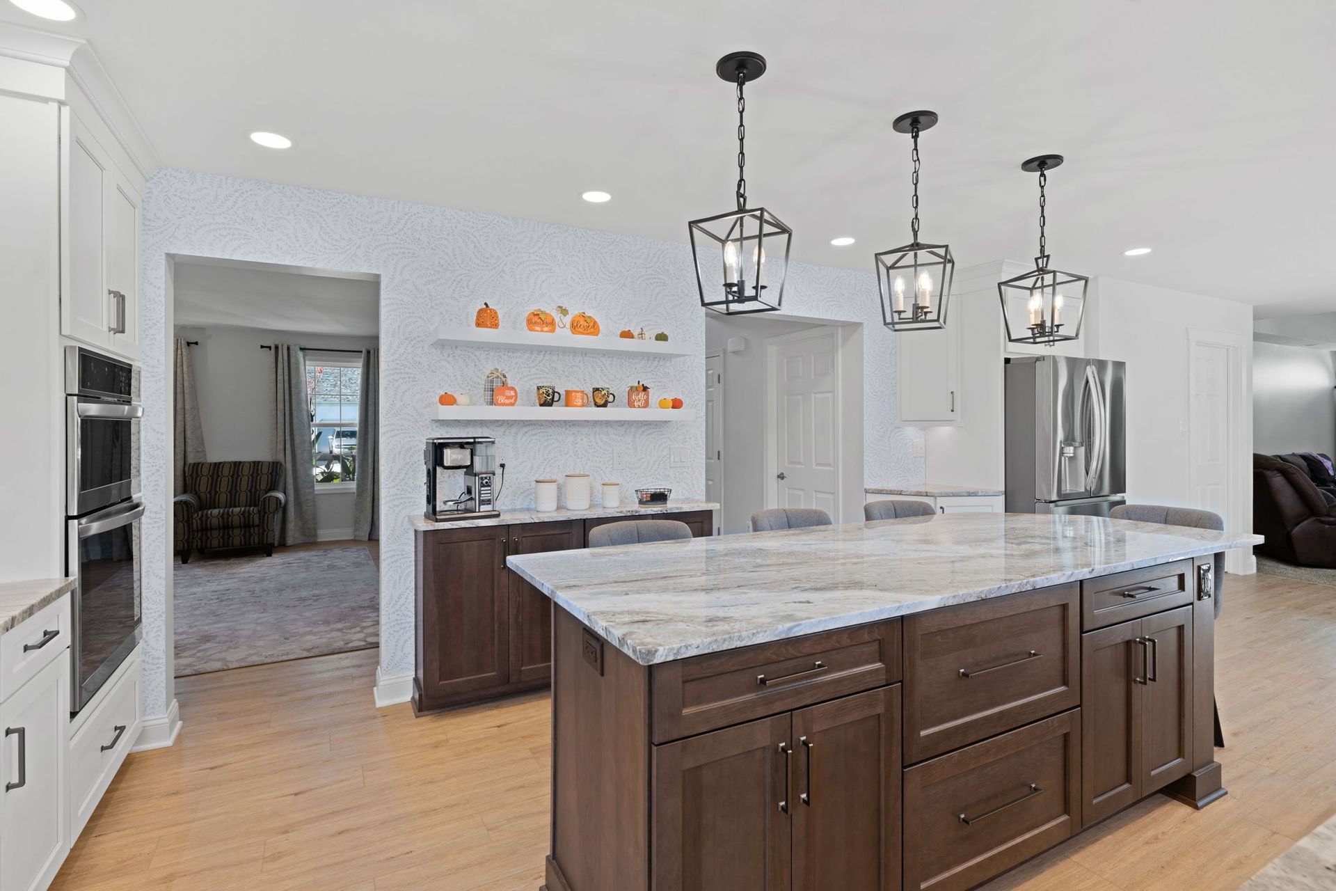Bright kitchen with large marble island, dark wood cabinets, and three pendant lights  In Bucks County PA