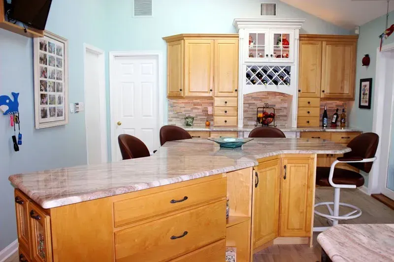 Bright kitchen with wood cabinets, a marble island, and white bar stools in Washington 