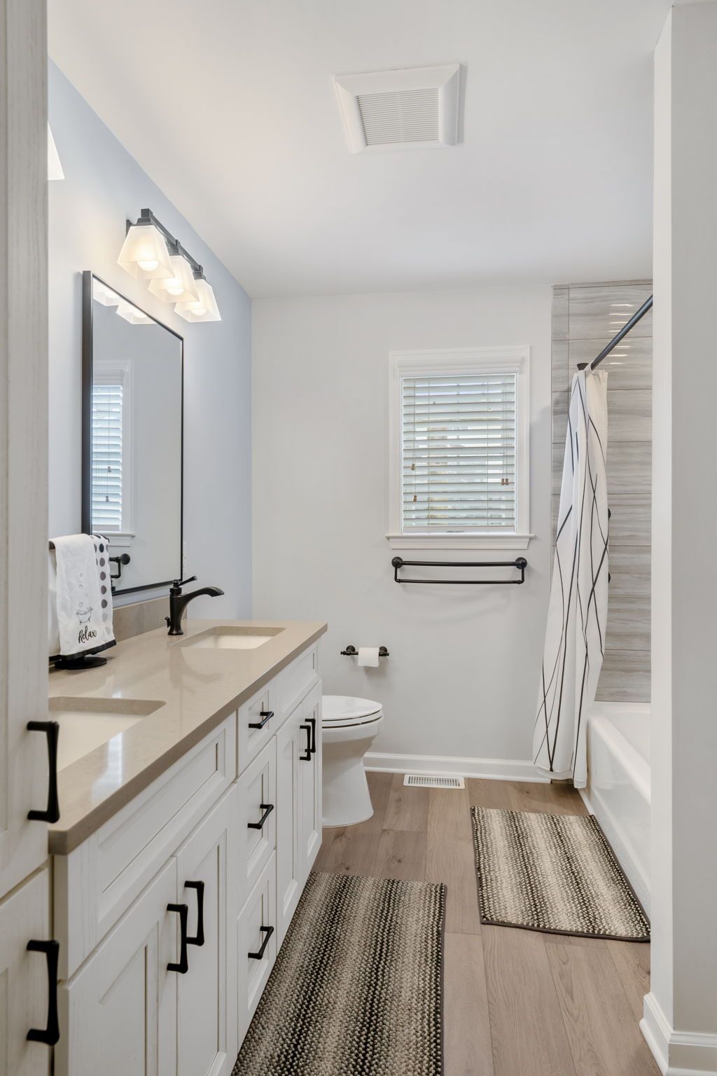 Bright bathroom with white vanity, shower curtain, and window blinds In Bucks County PA