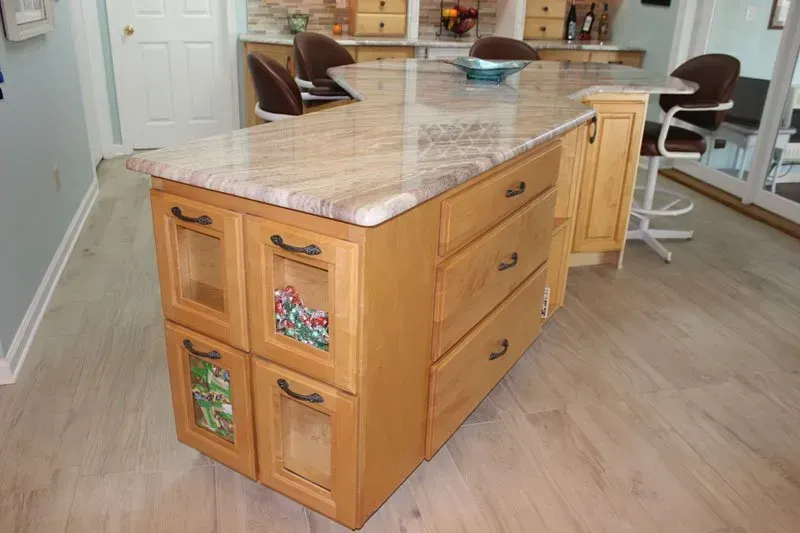 Wooden kitchen island with marble top in a bright room with bar stools and wood flooring in Washington 