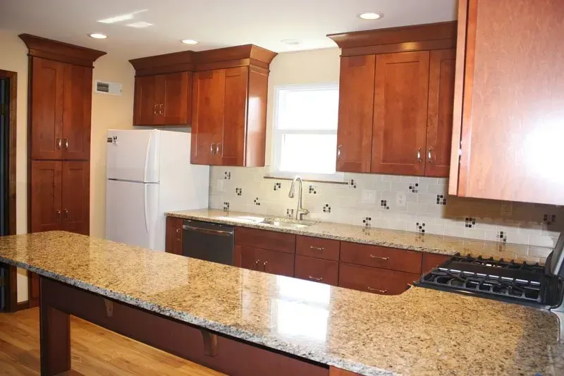 Spacious kitchen with wood cabinets, granite island, white fridge, and gas stovetop  In Bucks County PA