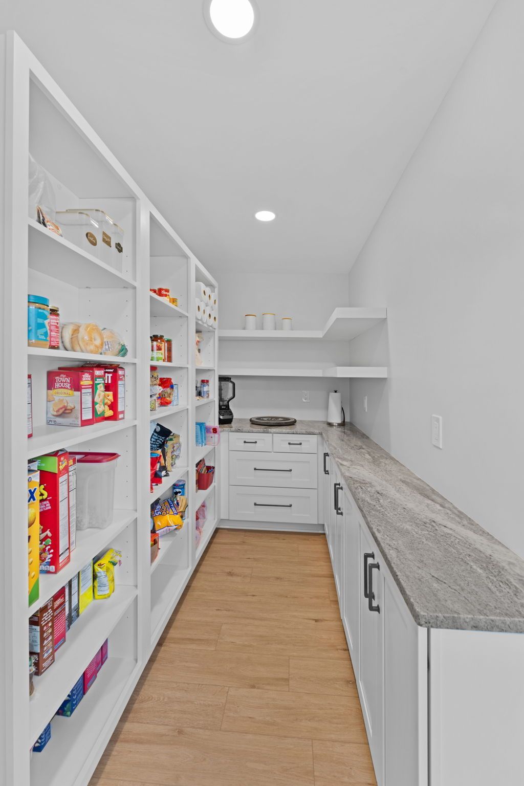 White pantry hallway with open shelves, wood floor, gray countertop, and built-in drawers  In Bucks County PA