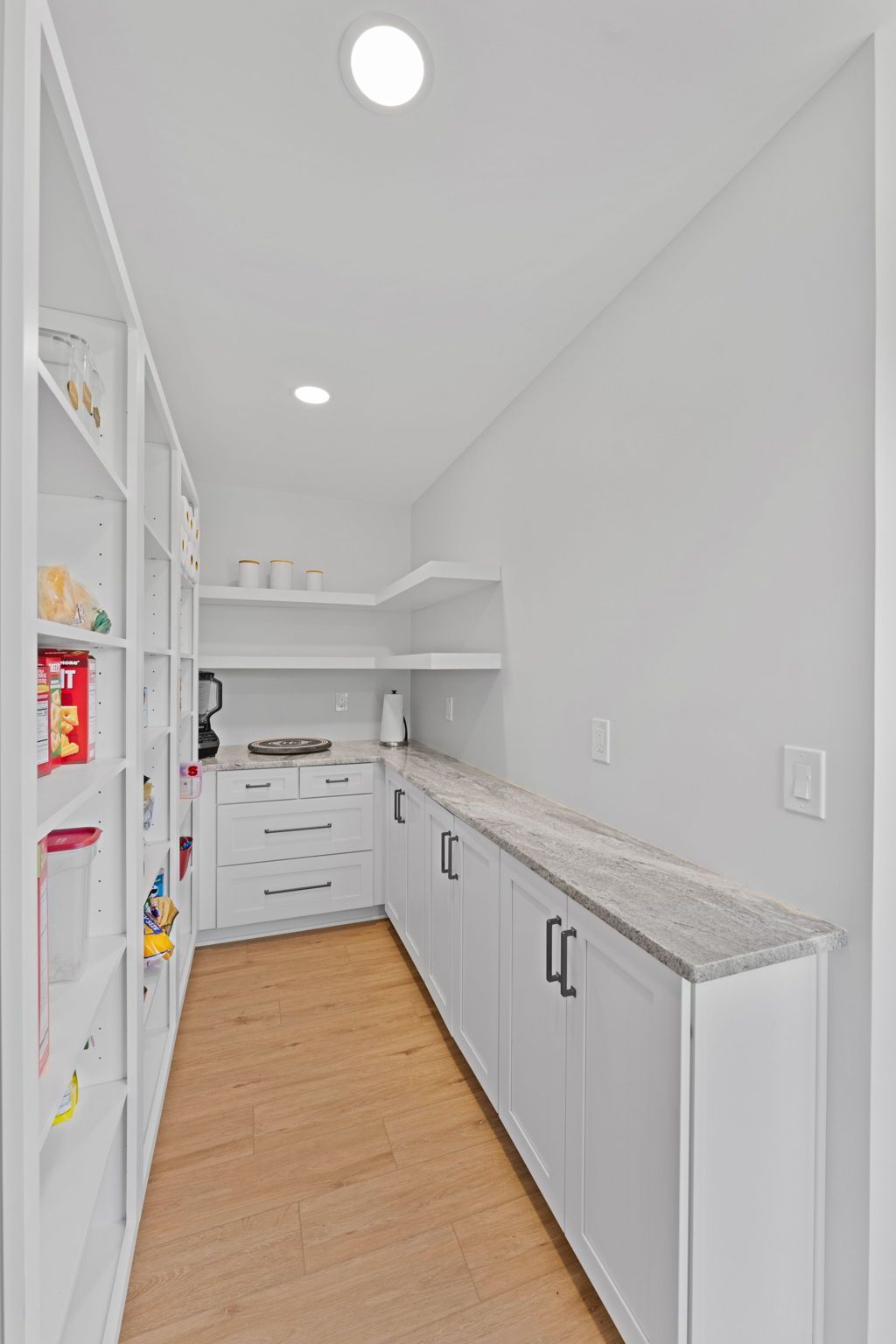 Bright white pantry or laundry room with built-in shelving, cabinets, and wood flooring  In Bucks County PA