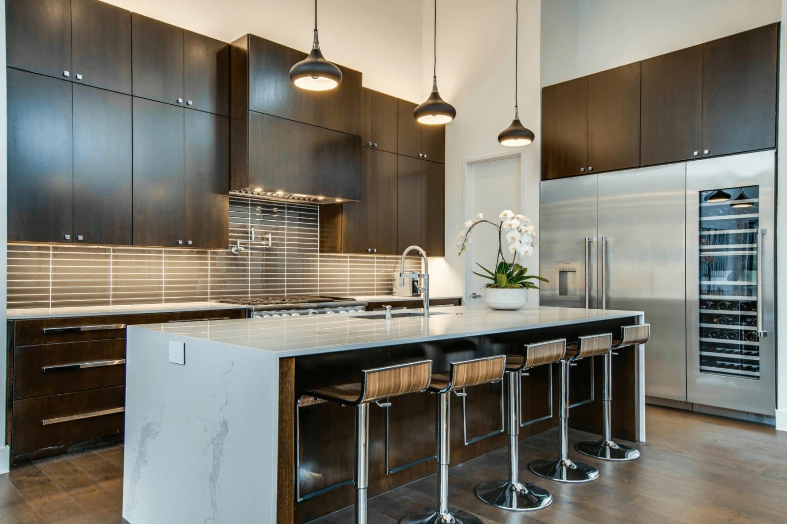 Modern kitchen with dark cabinets, marble island, bar stools, and stainless-steel appliances In Bucks Country PA