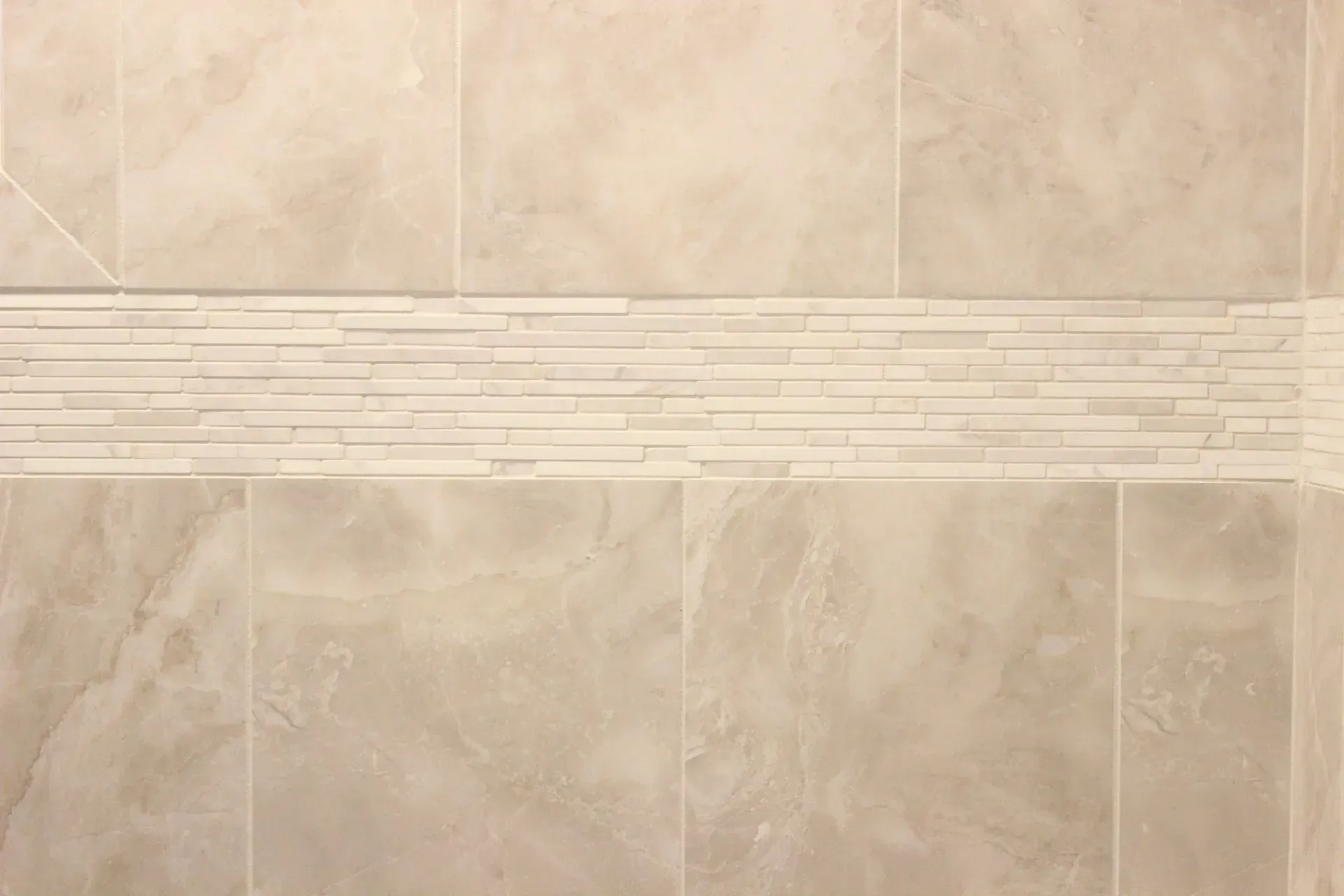 Beige tiled wall with a horizontal decorative mosaic strip across the center  In Bucks County PA