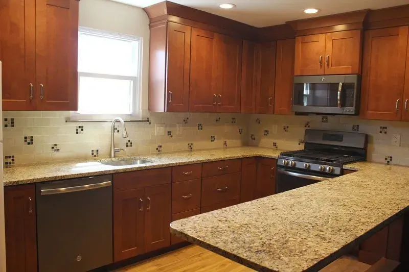 Modern kitchen with cherry cabinets, granite island, stainless steel appliances, and a window over the sink  In Bucks County PA