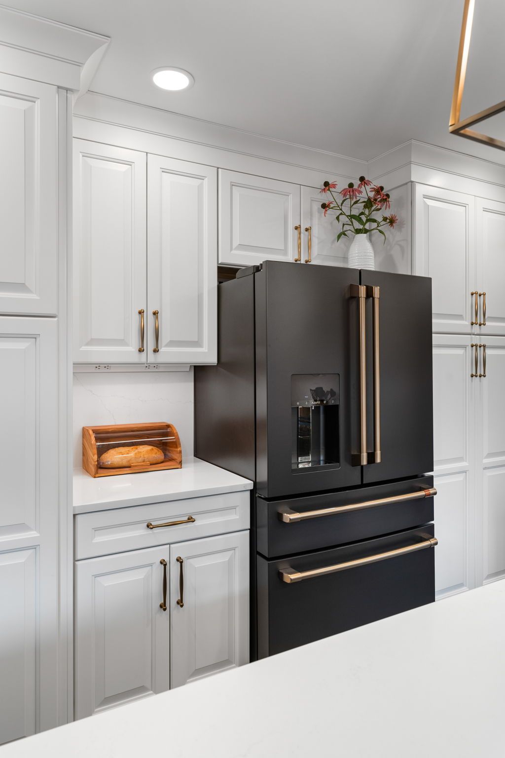 Modern kitchen with white cabinets and a matte black refrigerator with gold handles In Bucks Country PA