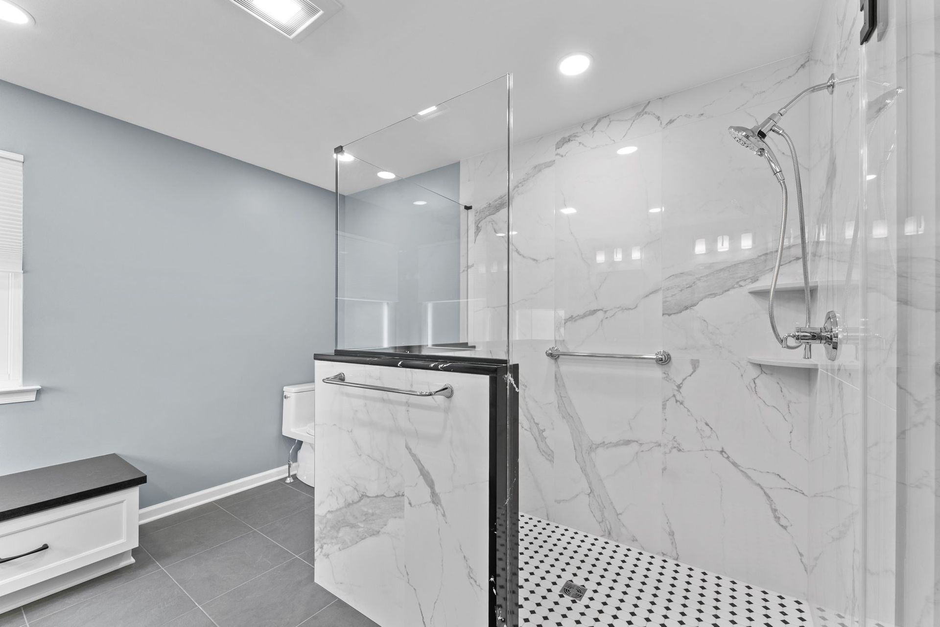 Modern bathroom with glass shower, marble tile, and white vanity In Bucks County PA