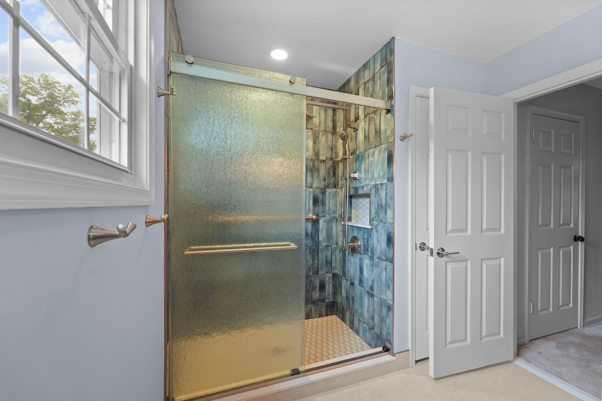 Modern bathroom with a gold-framed glass shower and double white doors beside it  In Bucks County PA