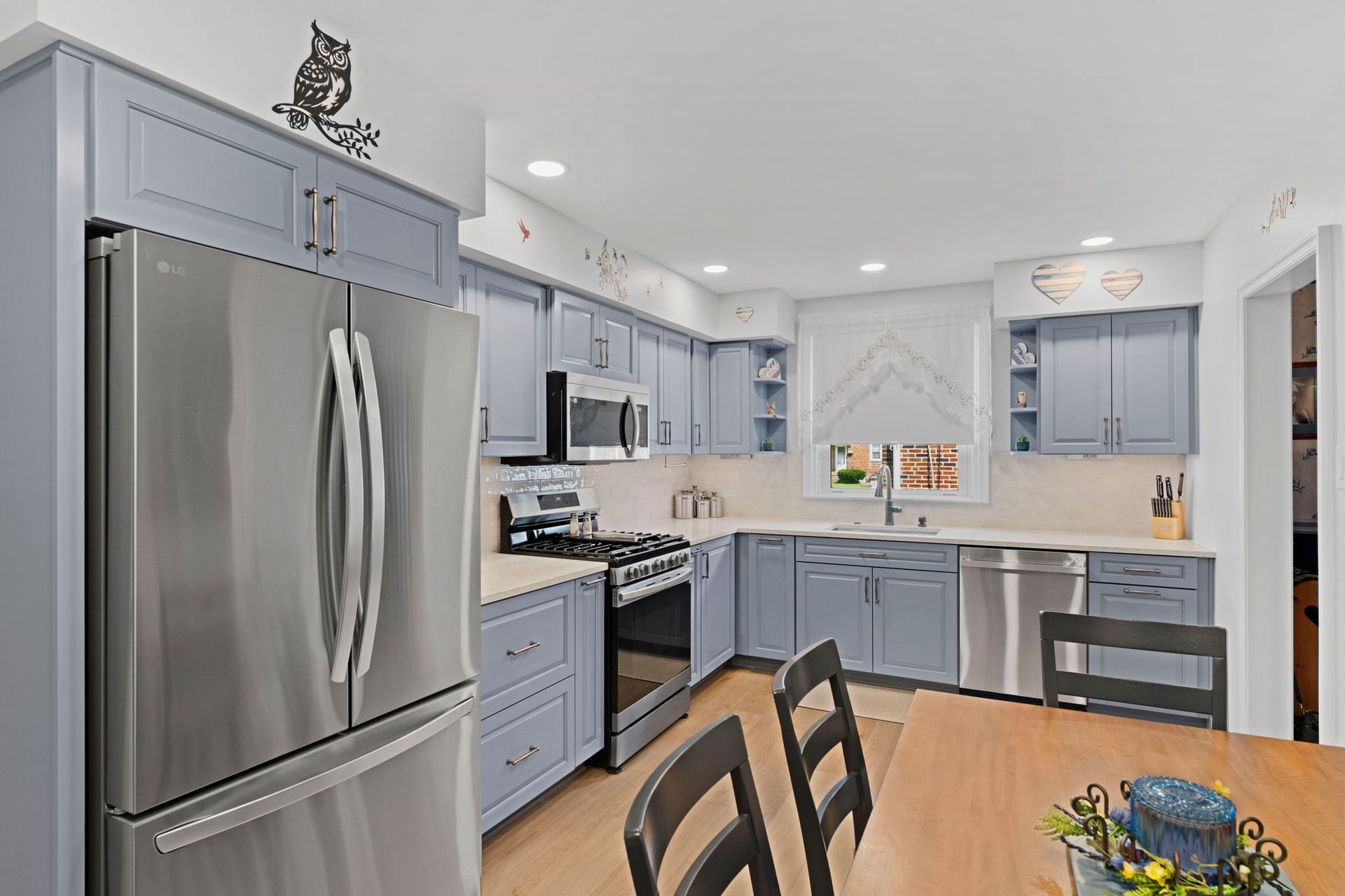 Bright kitchen with stainless steel fridge, light blue cabinets, and a wooden table by the window In Bucks County PA
