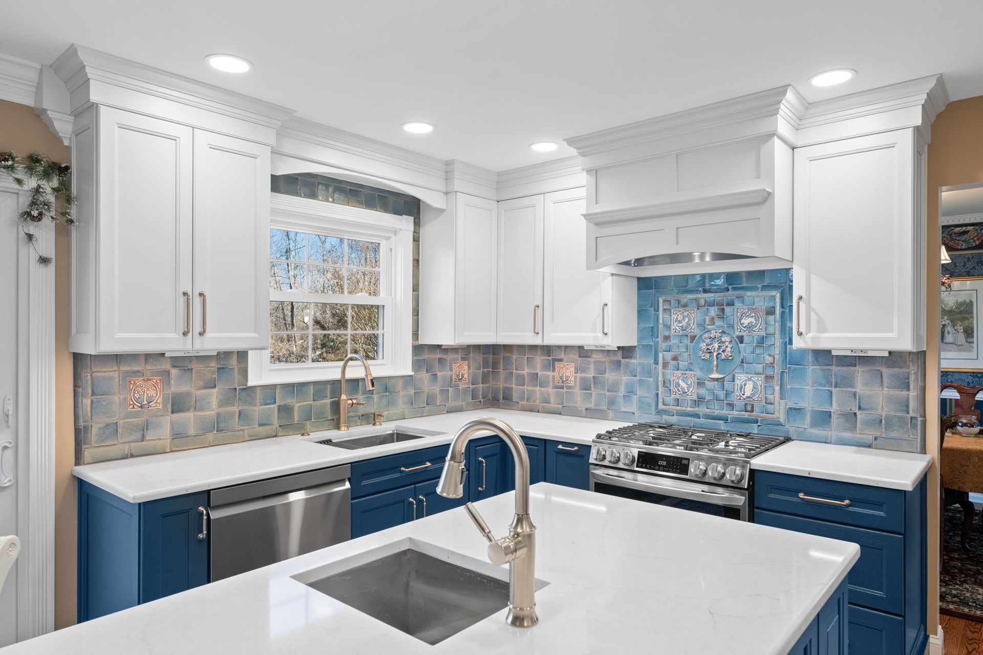 Bright white kitchen with blue cabinets, tiled backsplash, and a large island sink  In Bucks County PA
