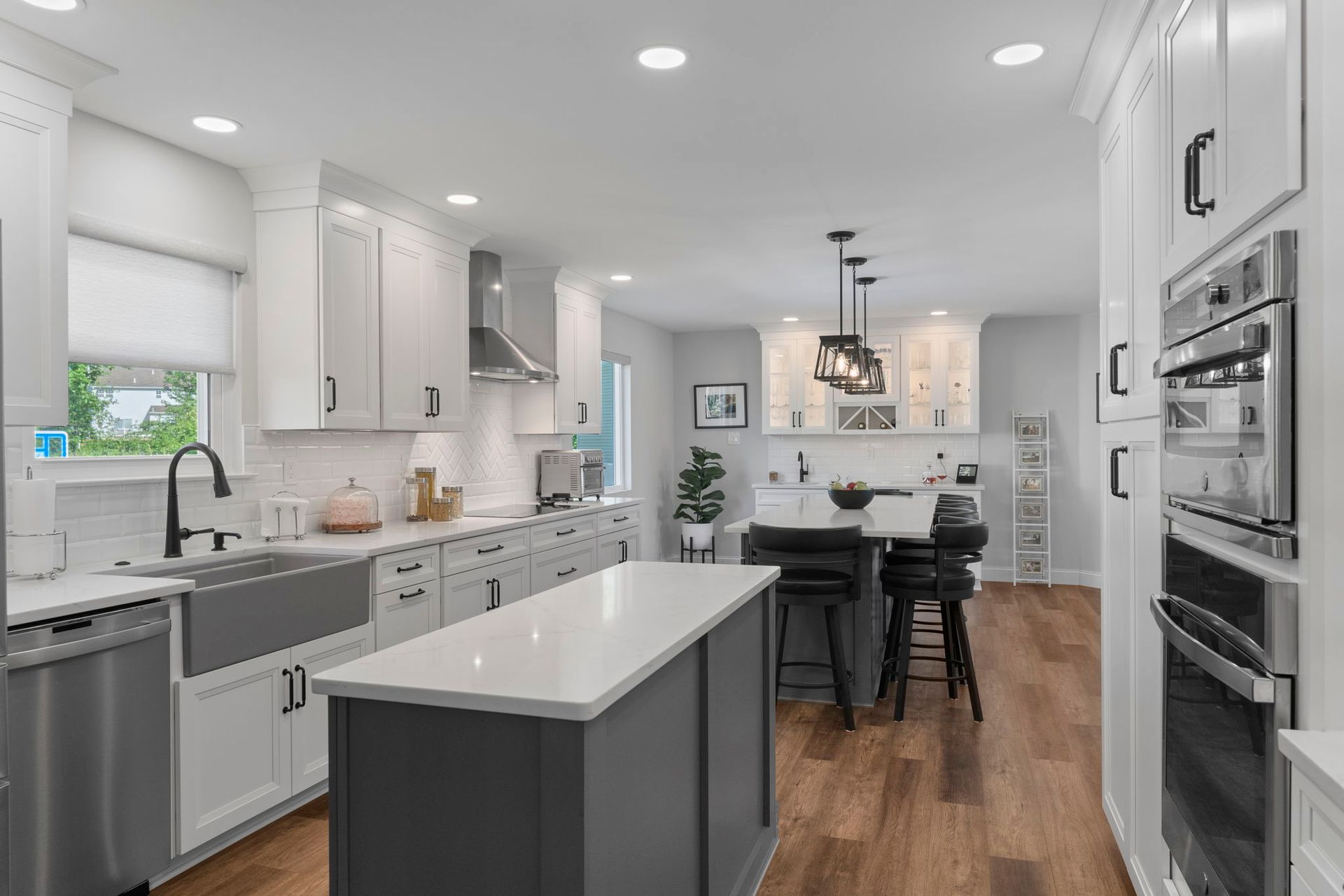 Bright modern white kitchen with island, stainless appliances, and dining area with black chairs In Bucks County PA