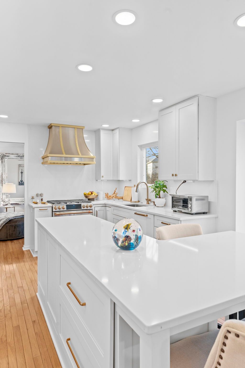 Bright white modern kitchen with gold accents, island, pendant light, and recessed ceiling lights In Bucks Country PA