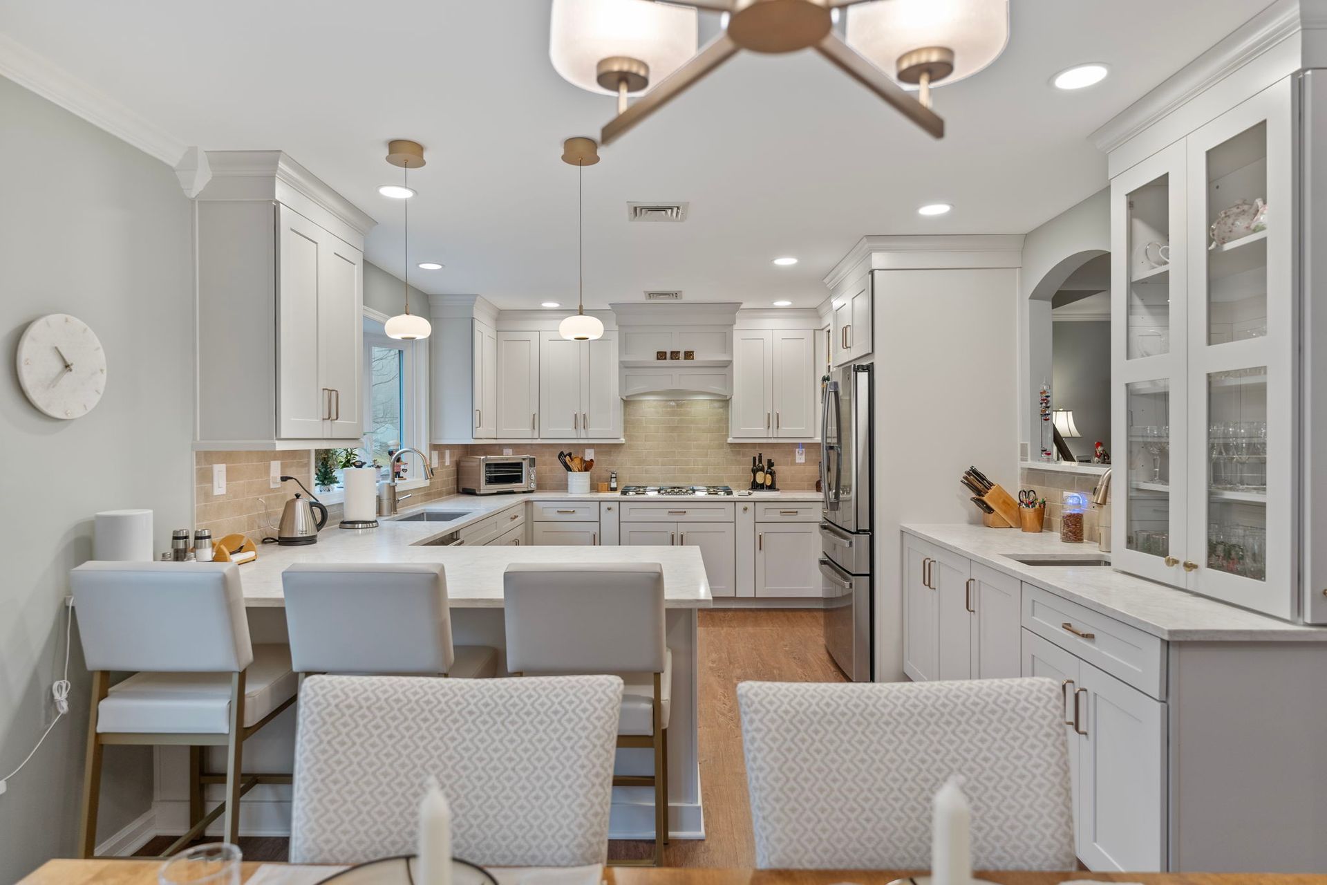 Bright white kitchen and dining area with island seating, cabinets, and glass-front display cabinets In Bucks Country PA