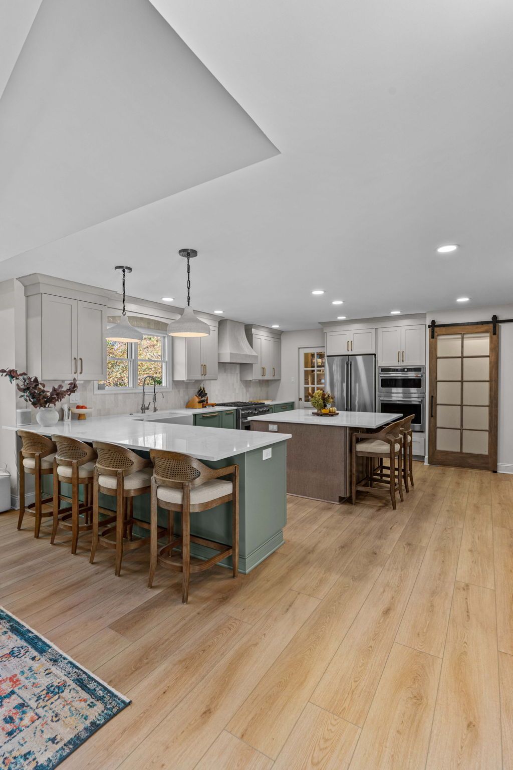 Bright open kitchen with island seating, white cabinets, wood floors, and pendant lights in Bucks Country PA