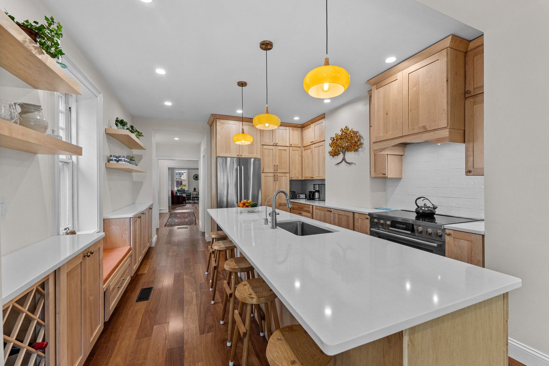 Modern kitchen with white island, light wood cabinets, pendant lights, and hardwood floor In Bucks County PA