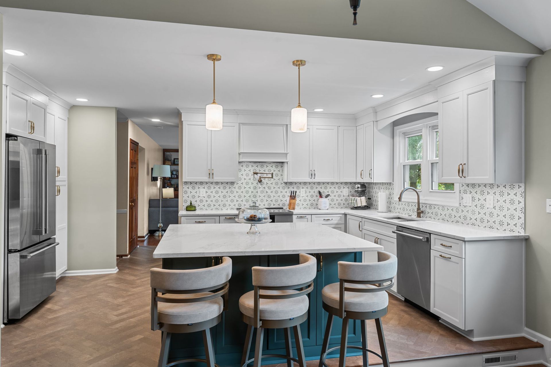 Bright white kitchen with island, three stools, pendant lights, and stainless steel appliances In Bucks County PA