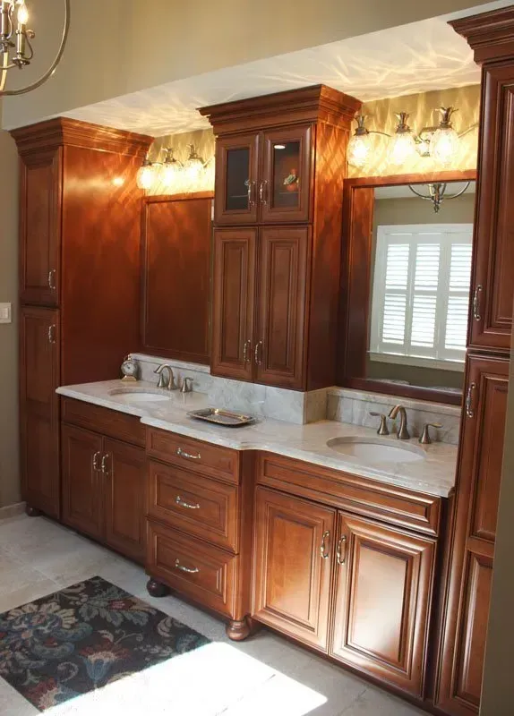 Wood-paneled bathroom vanity with marble countertop, mirror, and wall sconces In Bucks Country PA