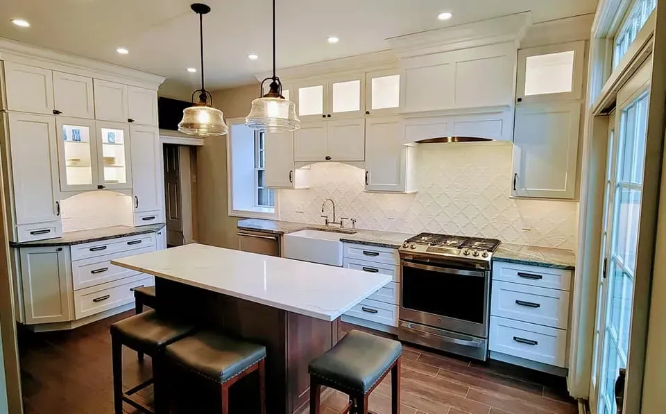 Bright white kitchen with island, pendant lights, stainless stove, and large windows In Bucks County PA