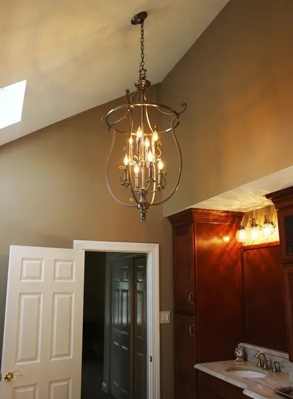 Kitchen or entryway with a hanging chandelier, white door, and dark wood cabinets under a vaulted ceiling In Bucks Country PA