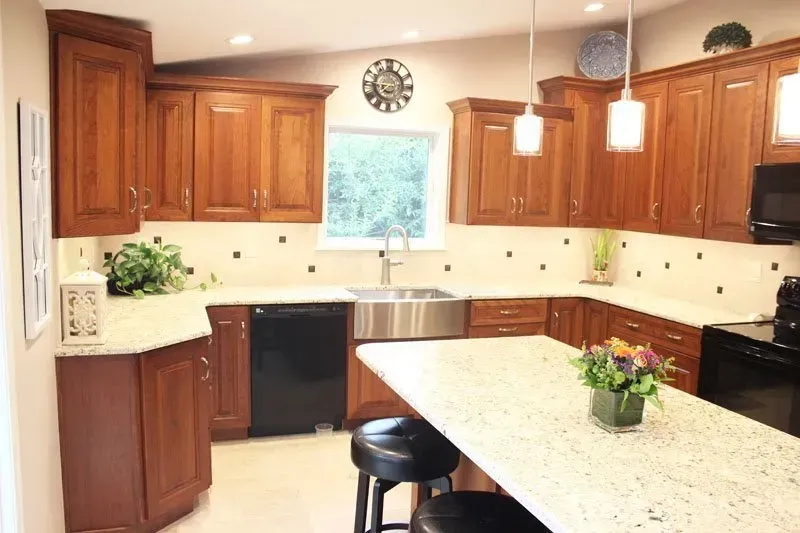 Bright kitchen with wood cabinets, granite island, pendant lights, and a window over the sink In Bucks County PA