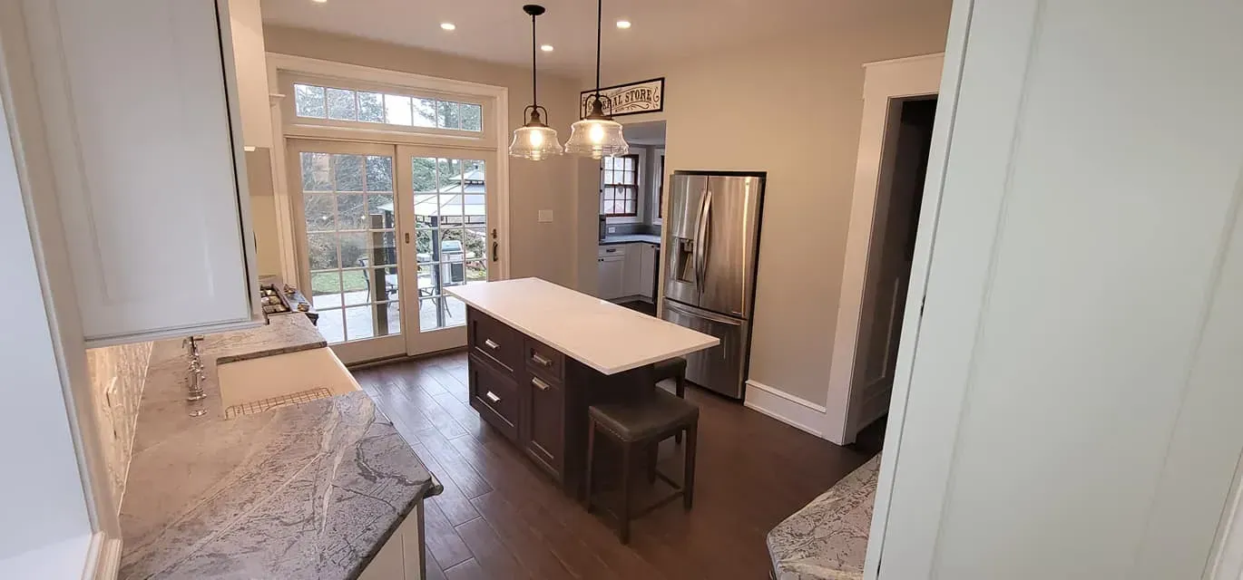 Bright kitchen with island, stainless refrigerator, pendant lights, and dining area in the background In Bucks County PA