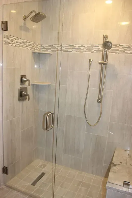 Glass walk-in shower with tiled walls, rainfall showerhead, handheld sprayer, and built-in bench In Bucks County PA